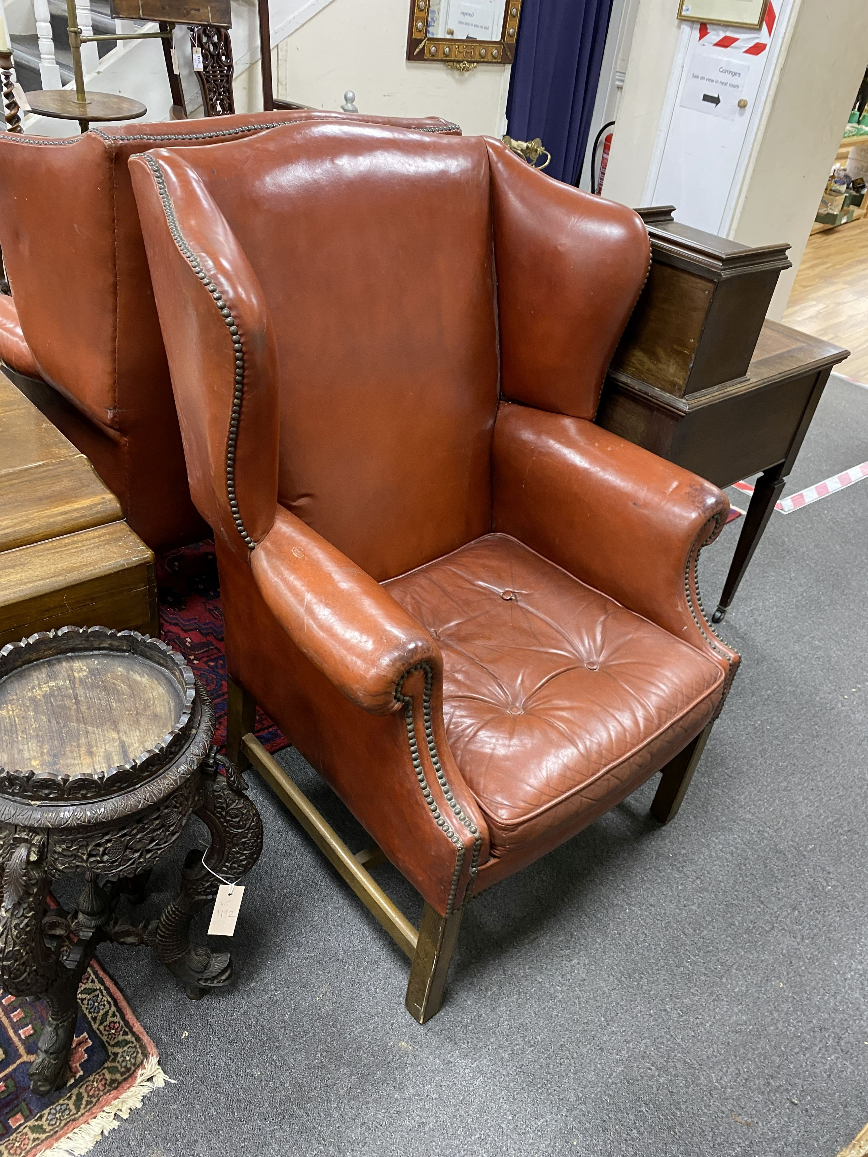 A pair of George III style studded red leather wingback armchairs, width 79cm